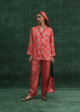 A model wearing a burnt orange silk PJ set with printed tigers and classic line detailing, featuring a front pocket and a relaxed fit.